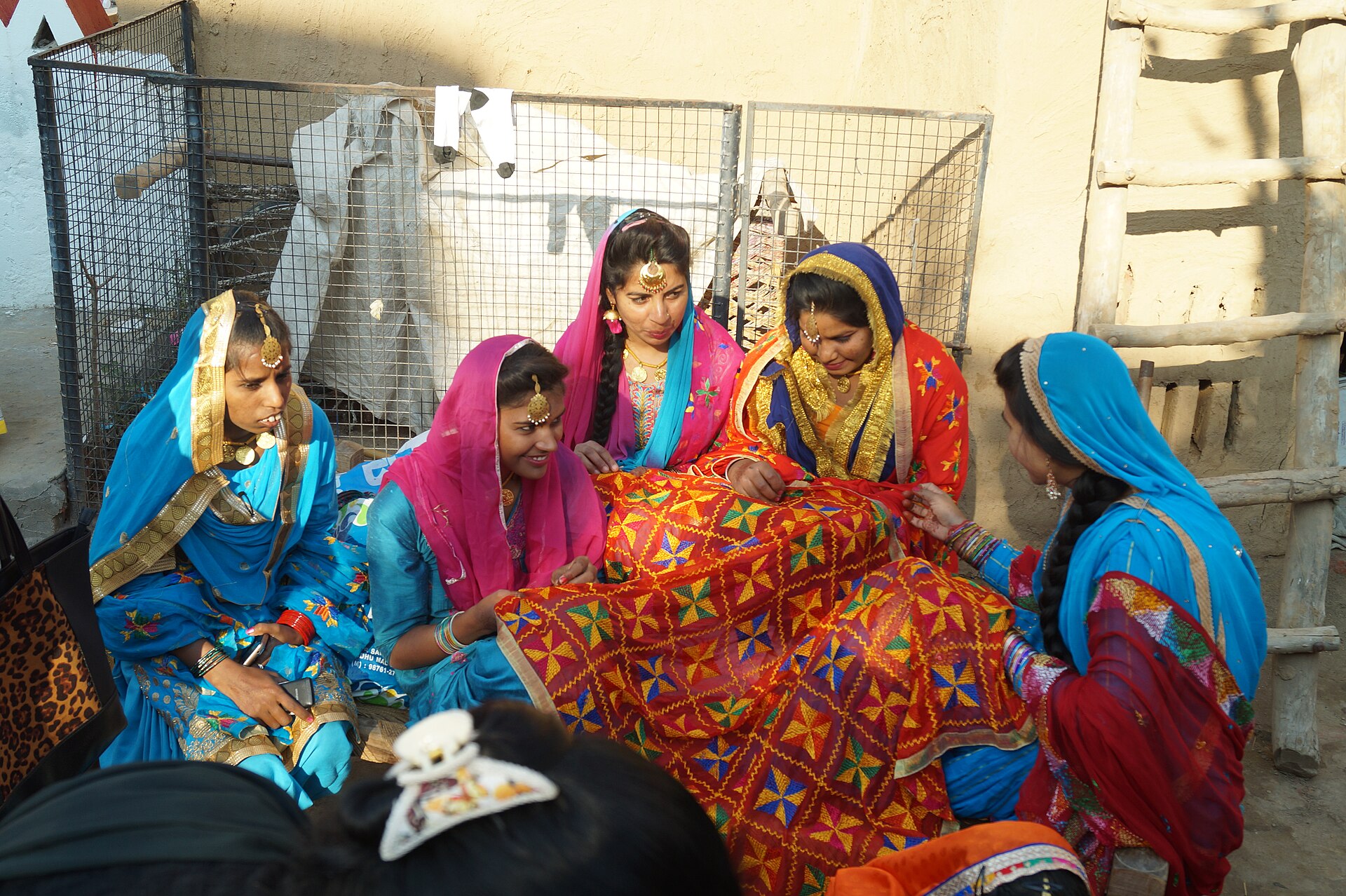 Women in traditional Punjabi dress admire a phulkari shawl at the Virasti Mela festival.